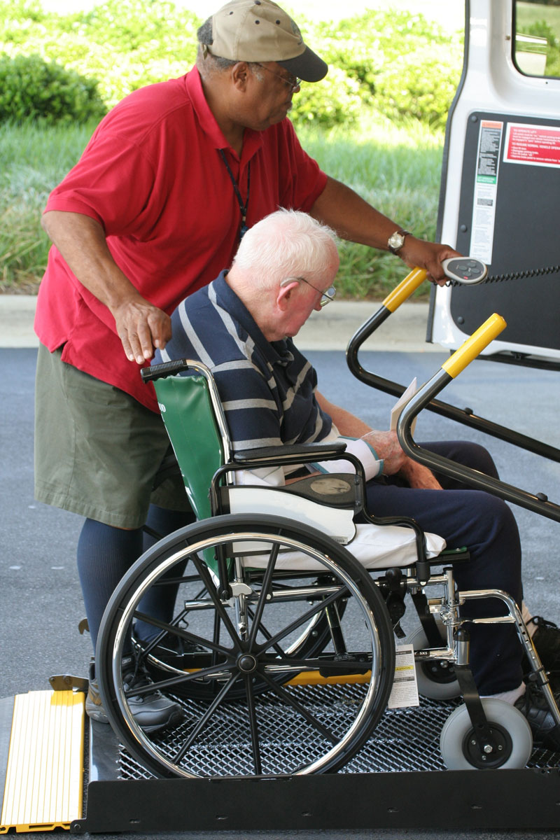 Assistance with transportation, man in wheelchair onto van lift